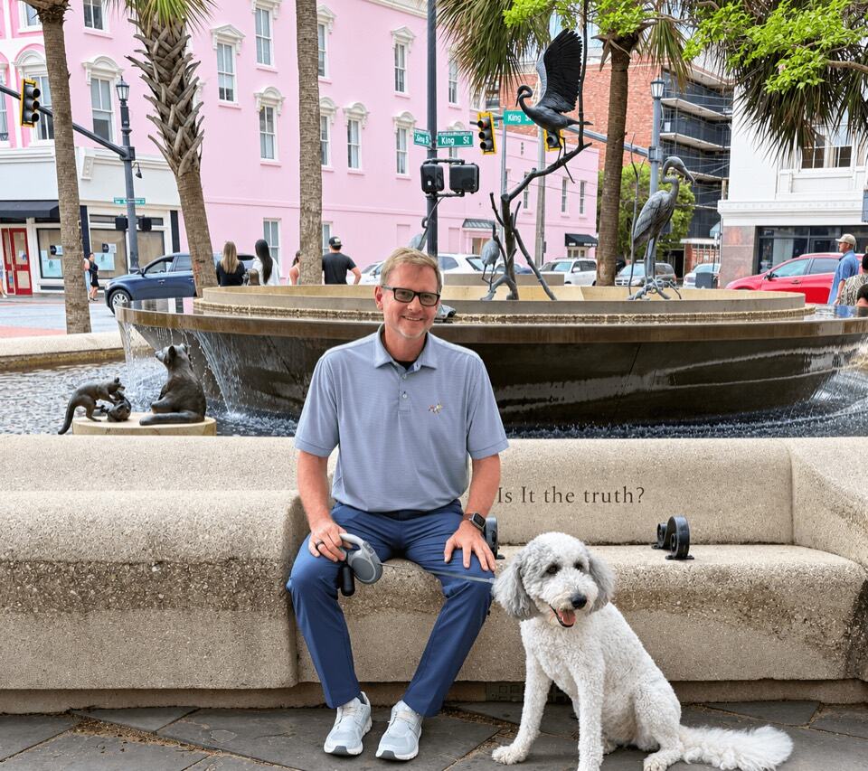 A team member sitting by a fountain with his dog