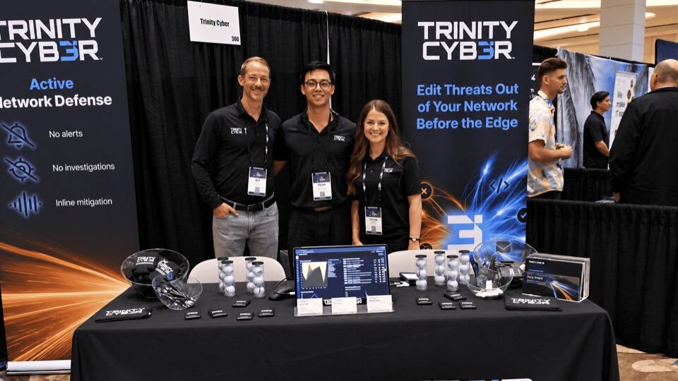 Three team members at the Trinity Cyber conference booth
